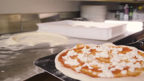 close up view of a chef holding pizza on a tray and inserting it into the stone oven