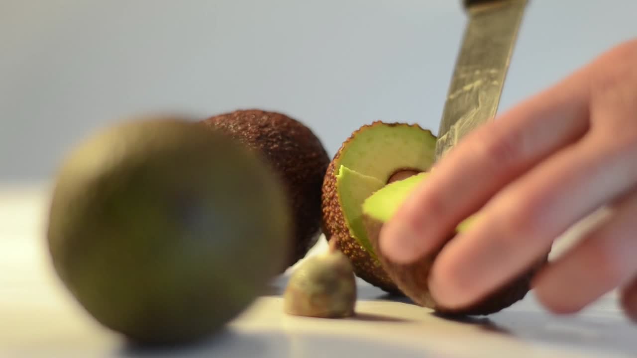 Fjernelse af midterkernen fra en skåret avocado med en kniv.