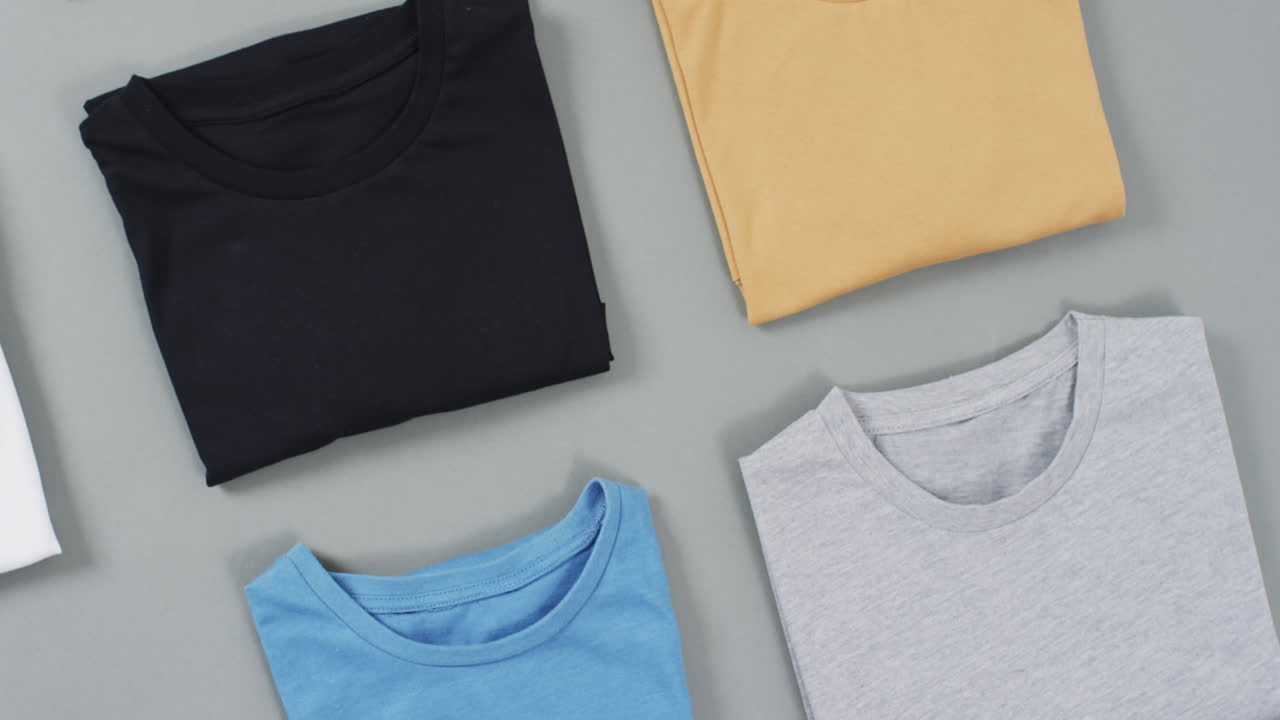Video of flat lay of t shirts with copy space on grey background