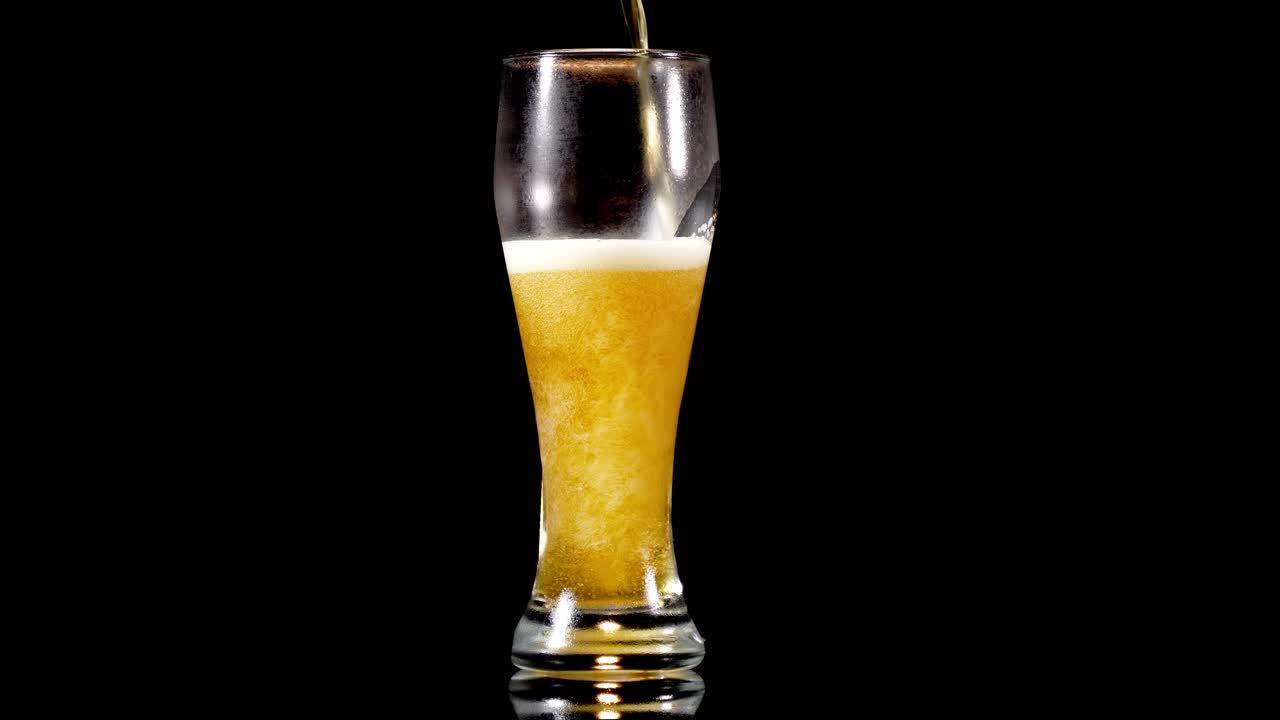 vaso weizen lleno de cerveza de trigo, burbujas espumosas en la parte superior aisladas en fondo negro
