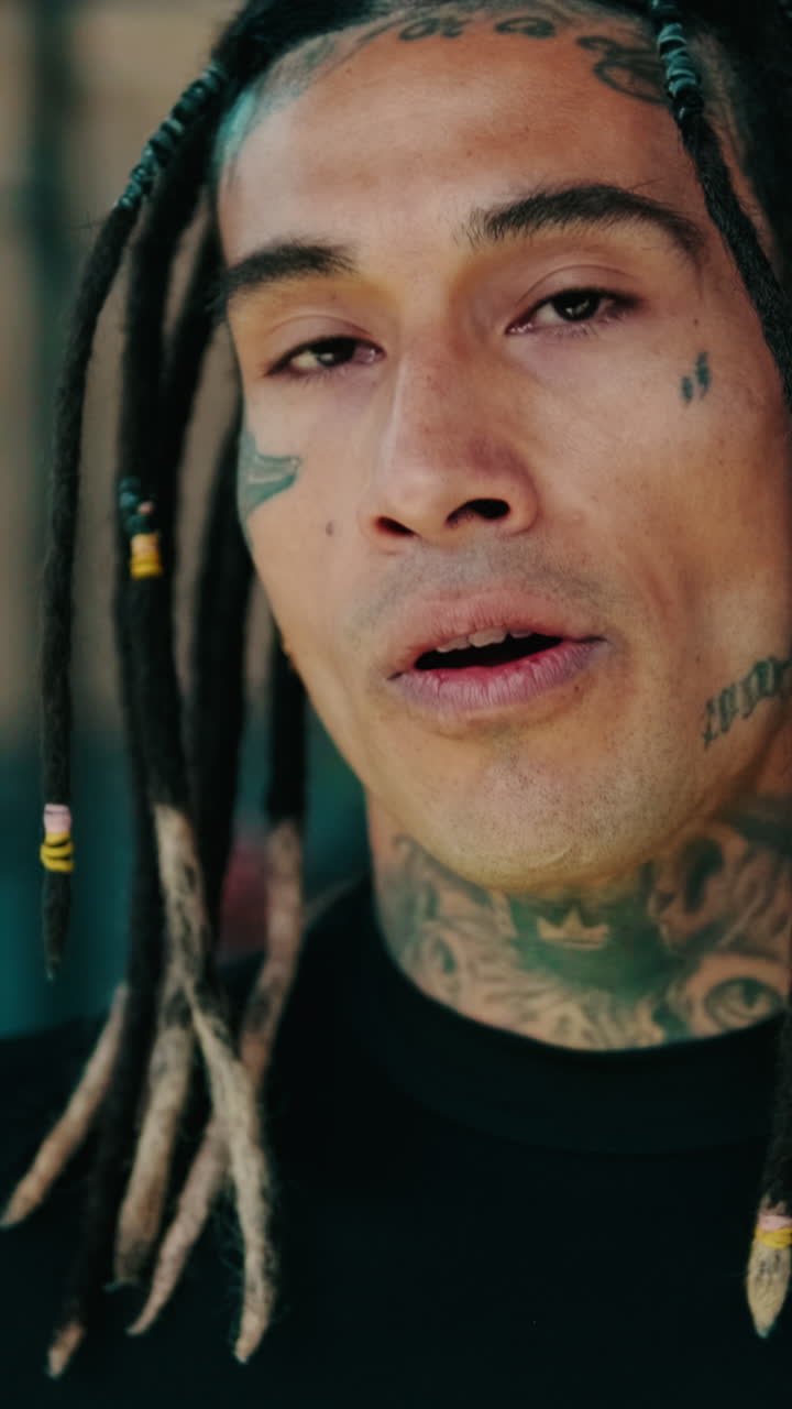 Ritratto di un uomo con dreadlocks e tatuaggi che parla