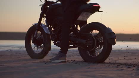 Unrecognizable-motorcyclist-thrusts-on-the-spot-with-the-rear-wheel,-evening-dusk