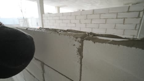 el maestro realiza la colocación de una pared de bloques de gas con herramientas y mortero adhesivo