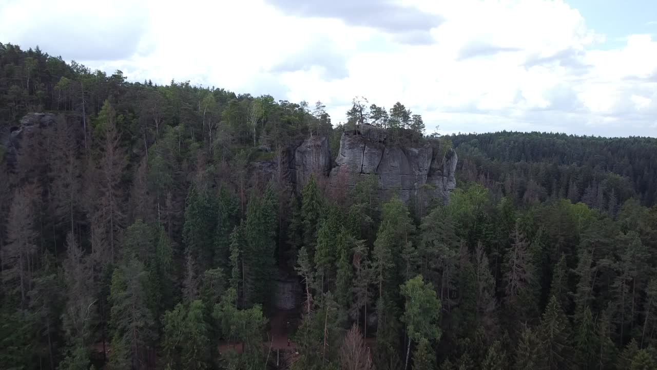 Drone flies over treetops and Rock formations in the Saxony Wilderness reserve Park with blue sky and clouds
