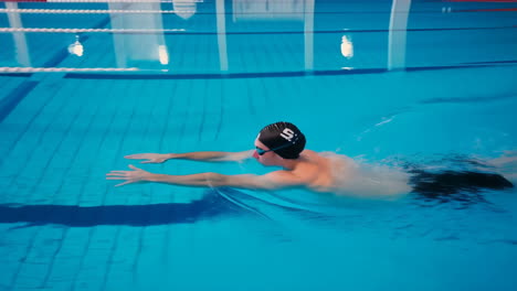 swimmer doing the butterfly stroke in an indoor pool