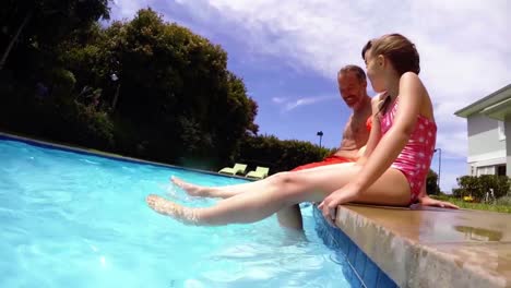 Padre-E-Hija-Sentados-Junto-A-La-Piscina-Y-Sacudiendo-Las-Piernas-En-El-Agua-De-La-Piscina