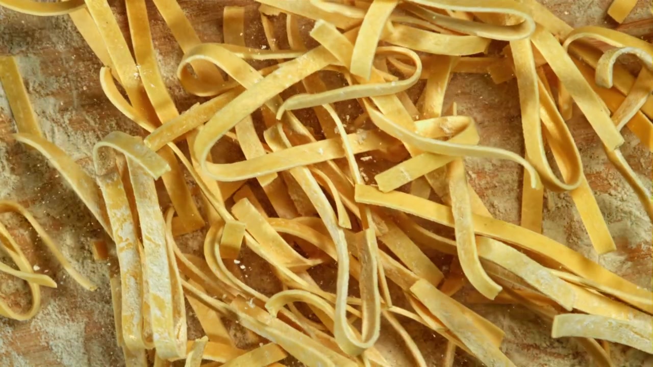 Primo piano di pasta fresca cruda con farina su un tagliere di legno