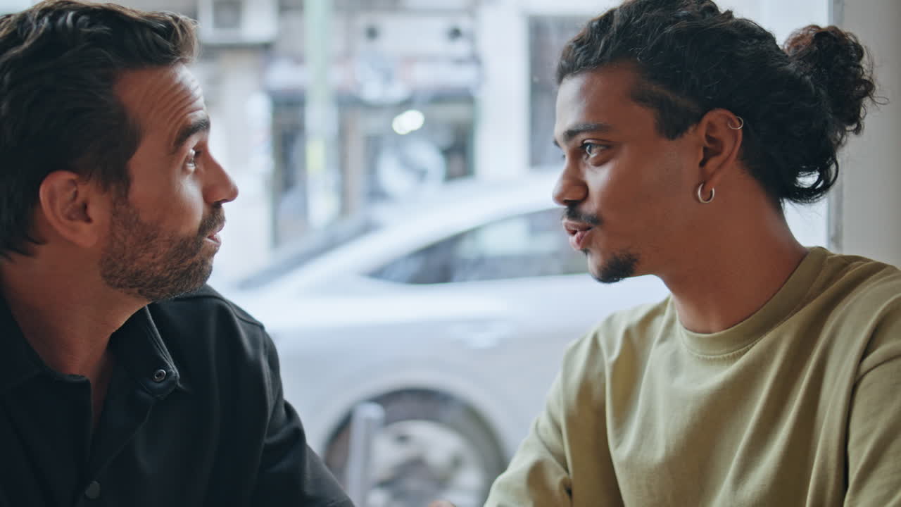 Joyful men talking coffeehouse smiling close up. Multiethnic guys conversation