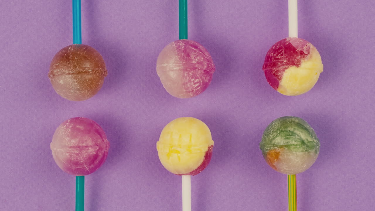 Sweet lollipops on color purple background zoom frame . Bright texture sugar candies close up top view. Composition of favorite children's summer sweets. Studio shot for shop, supermarket, confectionery