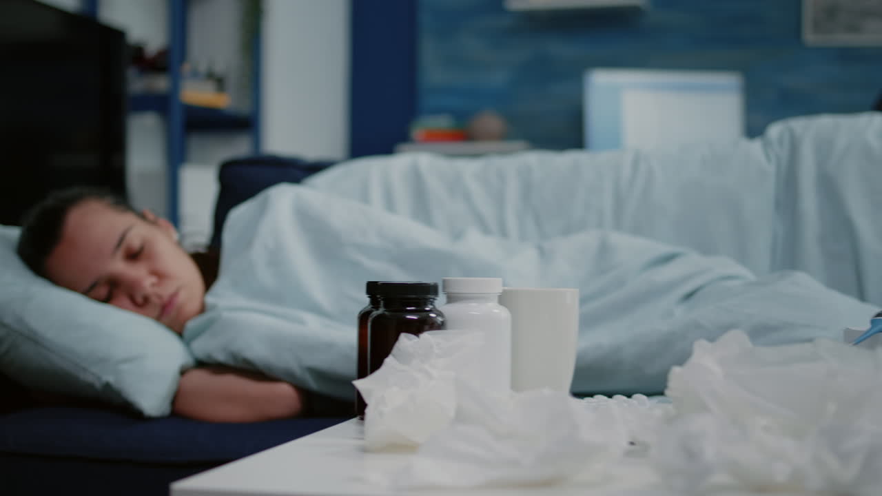 Close up of sick person laying on sofa wrapped in blanket