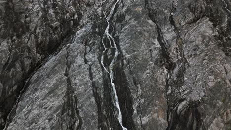 waterfall of a glacier on a steep rock face in the mountains, norway, europe, drone