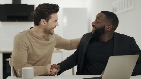 two businessmen shaking hands at open kitchen. happy partners discussing ideas.