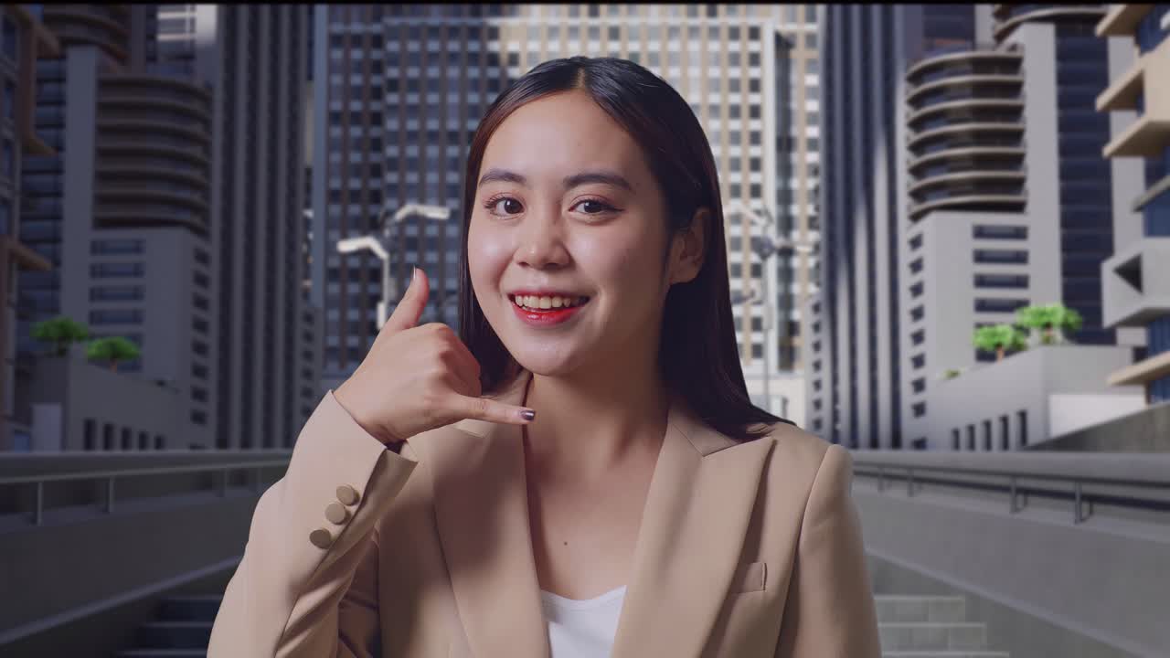 아시아 사업가 여성이 따뜻하게 미소 짓고 도시 거리에서 전화 제스처를 하고 있습니다.
