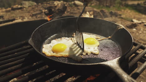 close up cooker using spatula to adjust two fried eggs in the pan