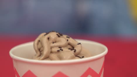 primer plano de chispas de chocolate cayendo sobre una taza de helado