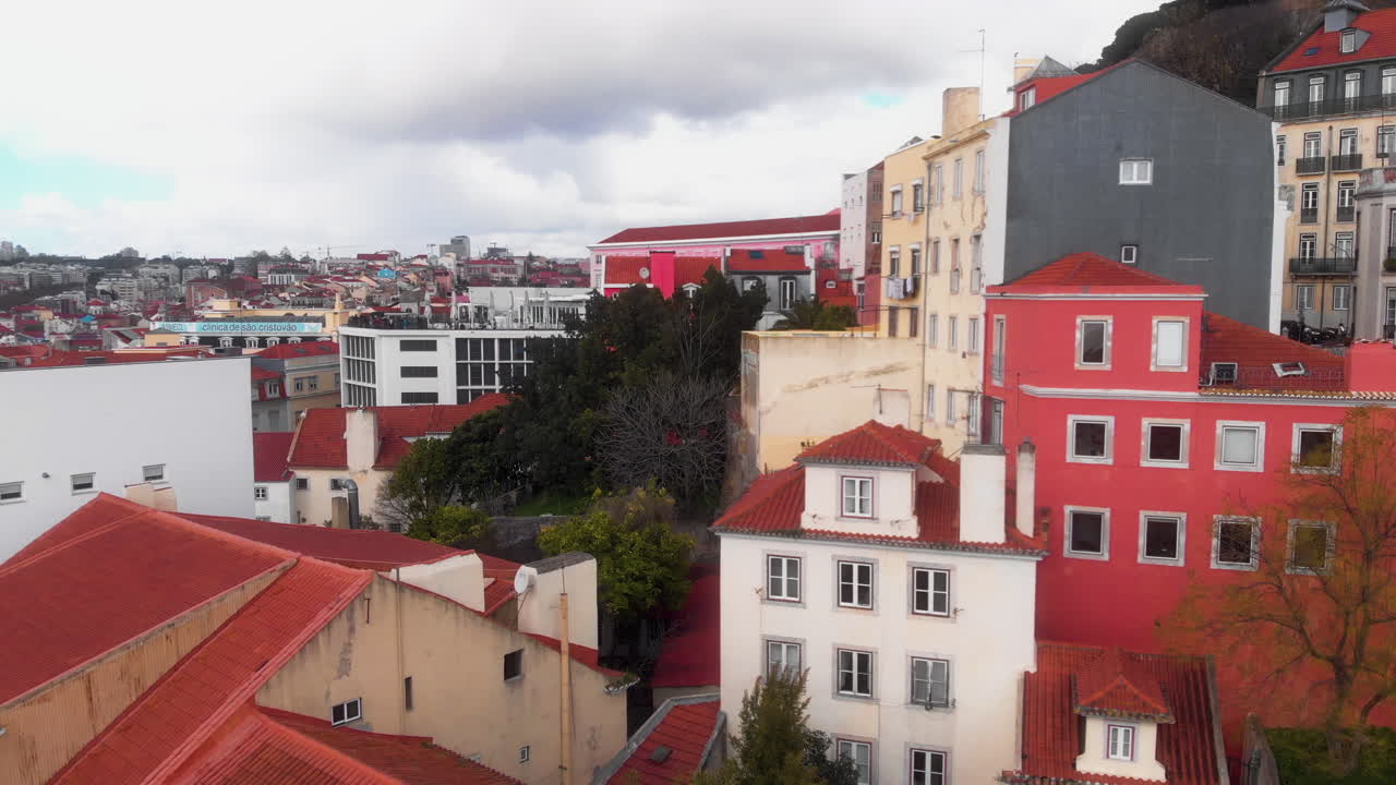 Drone orbitando ao redor de casas coloridas na encosta na cidade de Lisboa.
