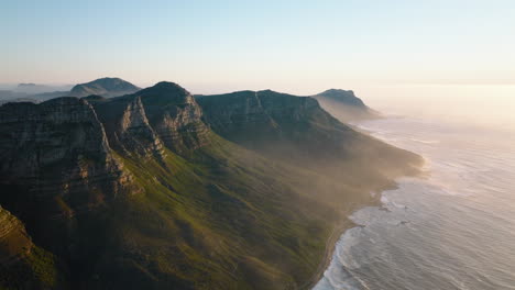 Erstaunliche-Aufnahmen-Von-Bergen-An-Der-Küste.-Grüne-Vegetation-Am-Hang,-Der-Sich-Aus-Dem-Meer-Erhebt-Und-Von-Einer-Felswand-Auf-Der-Spitze-Abgeschlossen-Wird.-Kapstadt,-Süd-Afrika