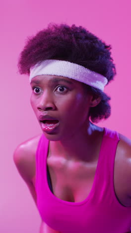 video vertical de una feliz y exitosa tenista afroamericana en un fondo rosa neón