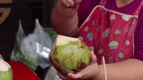 Woman-chopping-open-a-coconut-with-a-chopper