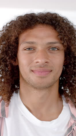 vertical video: a young biracial man with curly hair and blue eyes is pictured