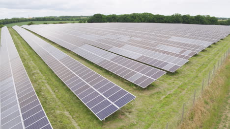 solar panel farm, aerial footage of large acre field covered in photovoltaic panels to the backdrop of a english countryside