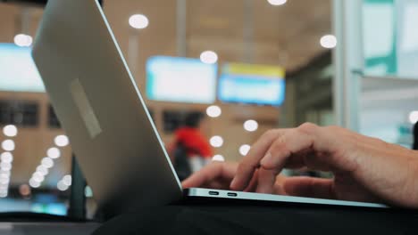 businessman uses laptop, waiting for a flight in airport terminal or train station, traveling entrepreneur working online on computer sitting in a boarding lounge of airline hub with airplanes