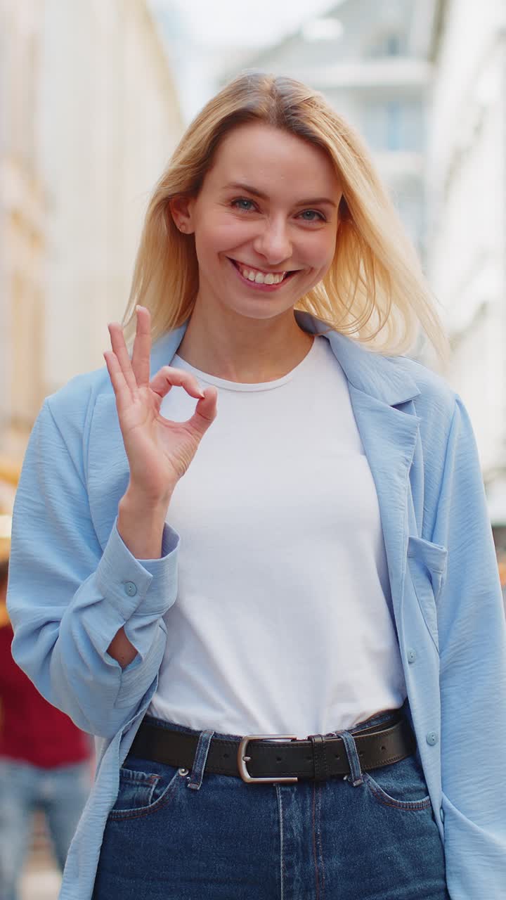 mujer joven mirando con aprobación a la cámara mostrando ok gesto positivo como señal ok celebrar la victoria