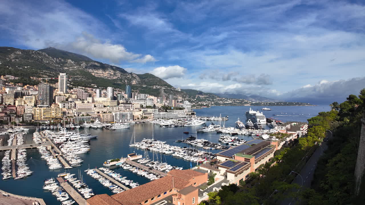 Vista dall'alto di Port de Fontvieille a Monaco, con edifici colorati, yacht di lusso e il paesaggio montuoso circostante