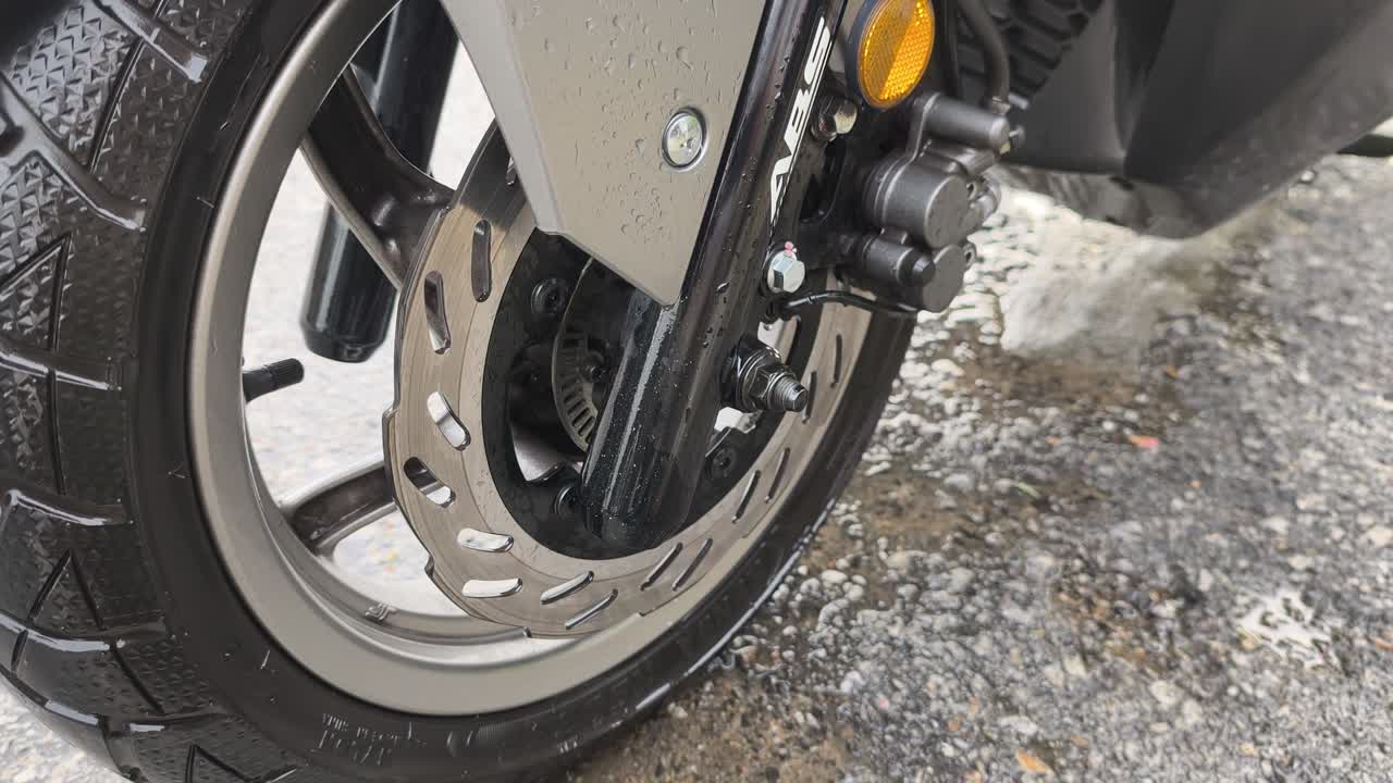 Close-up of a scooter's disk brake system, featuring ABS and TCS technology. This system is crucial for safety when navigating wet and slippery roads