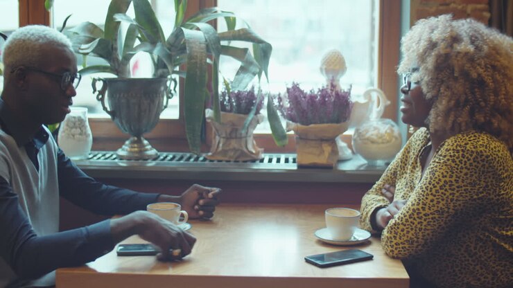 afrikanisch-amerikanischer mann und frau unterhalten sich über einen kaffee in einem café.