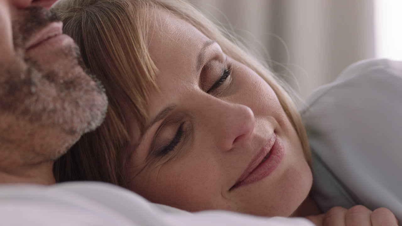 행복한 젊은 커플이 침대에 누워  ⁇ 안고 로맨틱한 관계를 나누고 아름다운 여성이 파트너와 친밀감을 즐기고 집에서 함께 휴식을 취하고 있습니다.