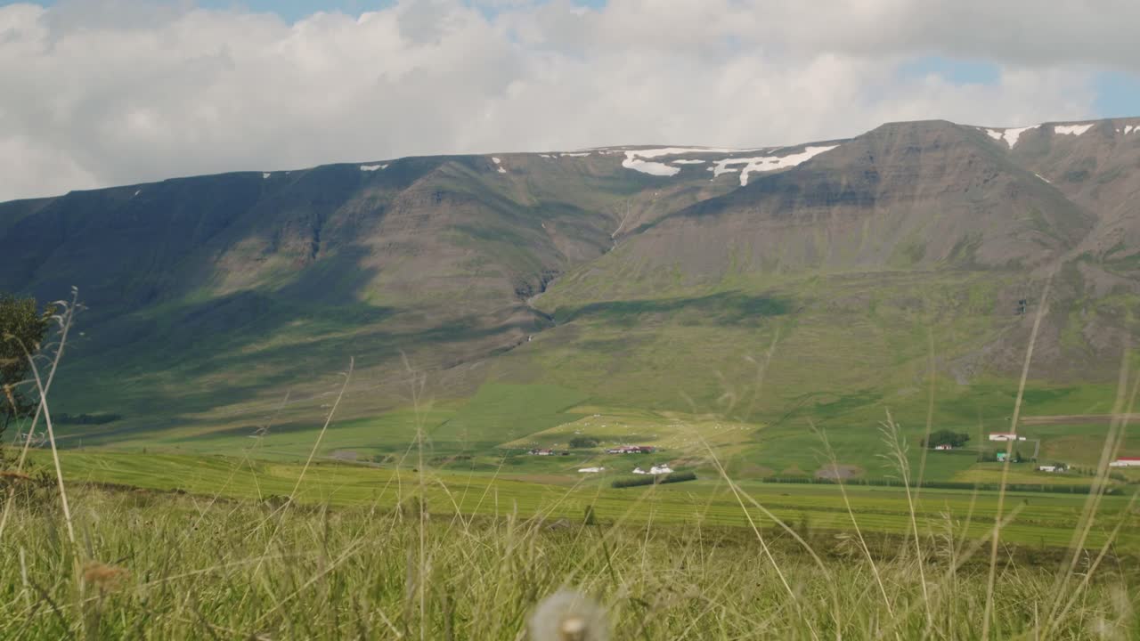 Timelapse av fält och vackra snötäckta toppar på norra Island när molnskuggorna rullar över bergen.