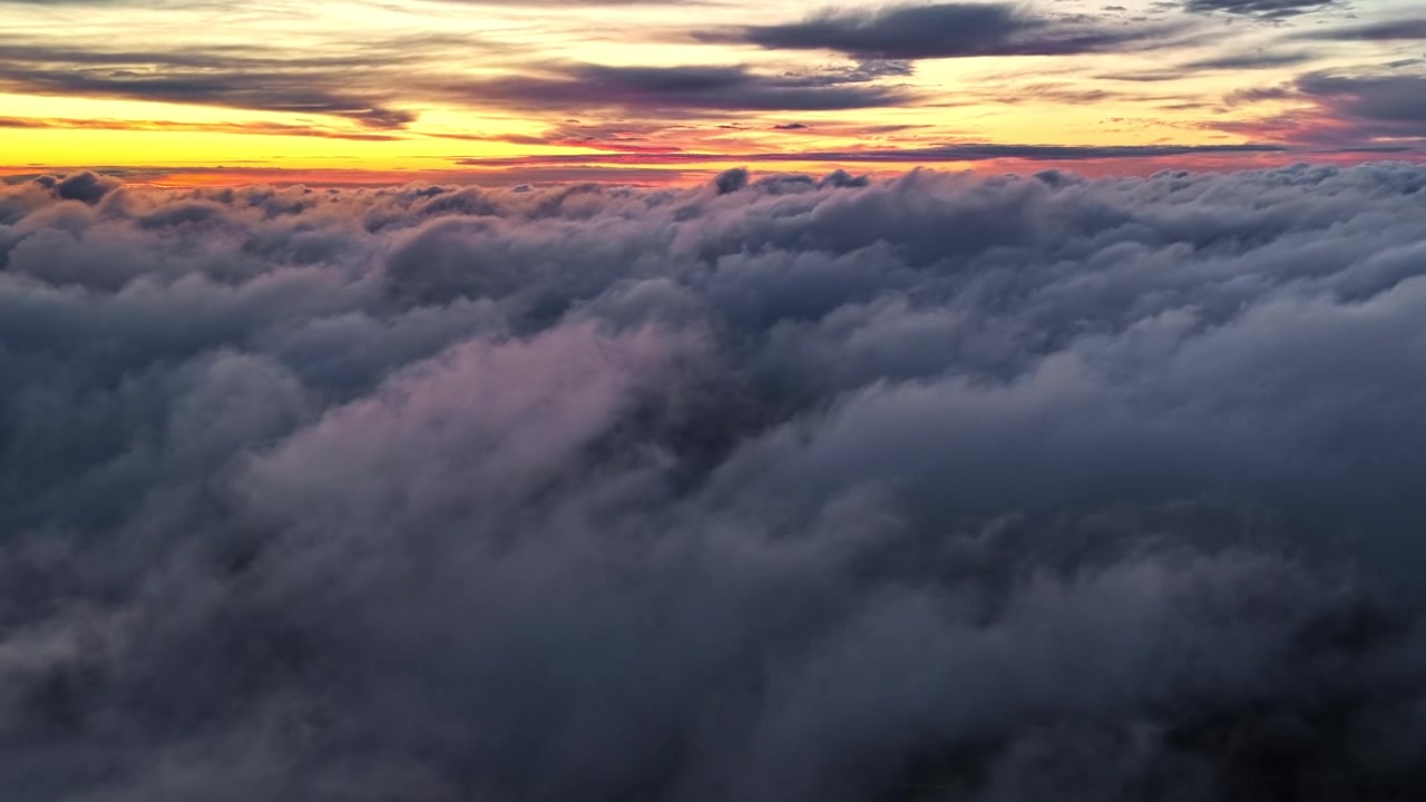 Vibrant sunset hues illuminate a vast sea of clouds, creating a captivating aerial view. Perfect for atmospheric scenes or weather-related content.