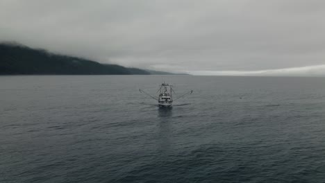 fishing trawler sailing on the calm water by the saint lawrence on a foggy day in quebec, canada