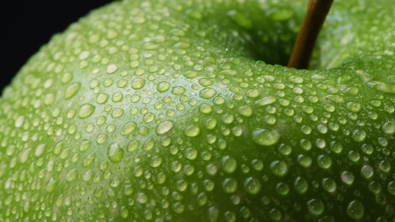 Primo piano di una deliziosa mela verde fresca e croccante con goccioline d'acqua.