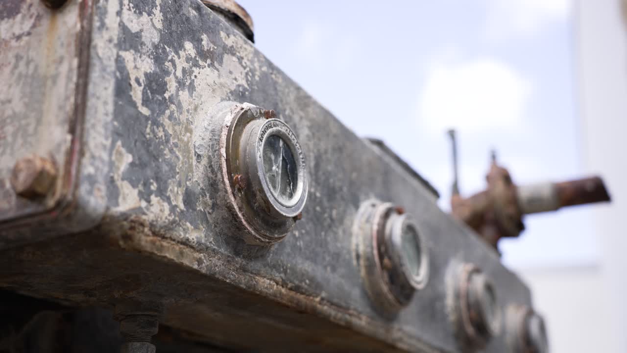 Gammel stationær motor med rustent metal og afskallende maling, der fremhæver industrihistorie