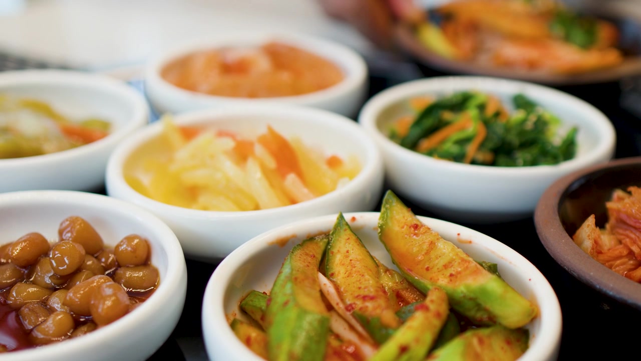Close-up statis menampilkan berbagai lauk Korea fermentasi yang tersusun di atas meja.