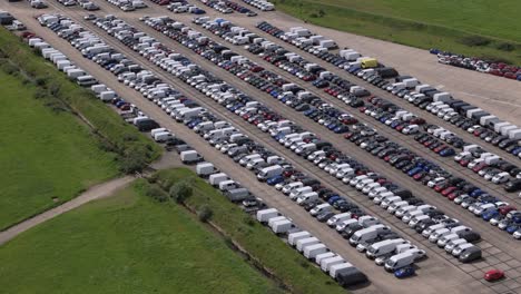 Thousands-of-unwanted-new-and-used-motors-aerial-view-stored-on-RAF-Thurleigh-airfield-runway,-Bedfordshire,-England