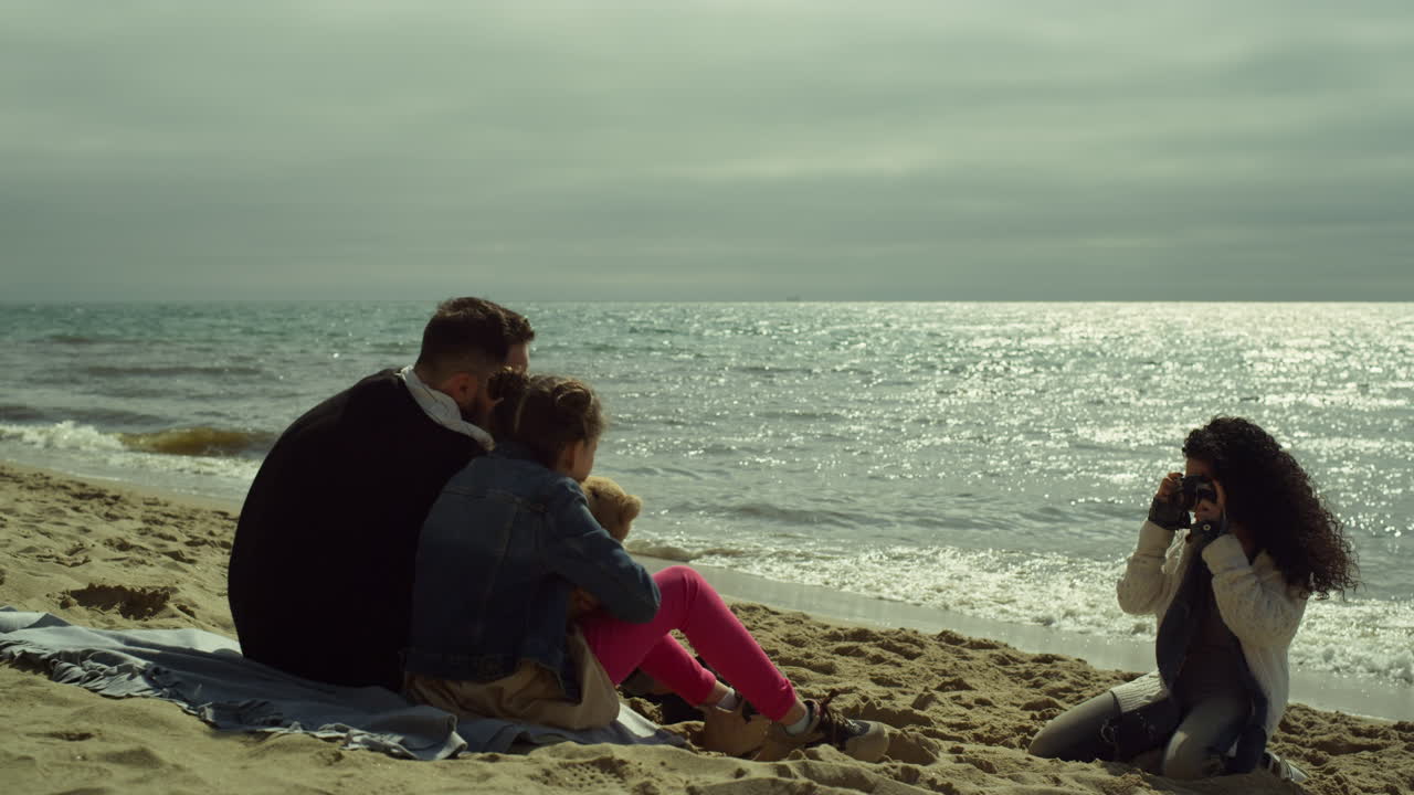 부모가 해변 바다에서 포즈를 취하는 아이. 젊은 가족이 반 ⁇ 이는 바다에서 카메라 사진을 찍고 있습니다.