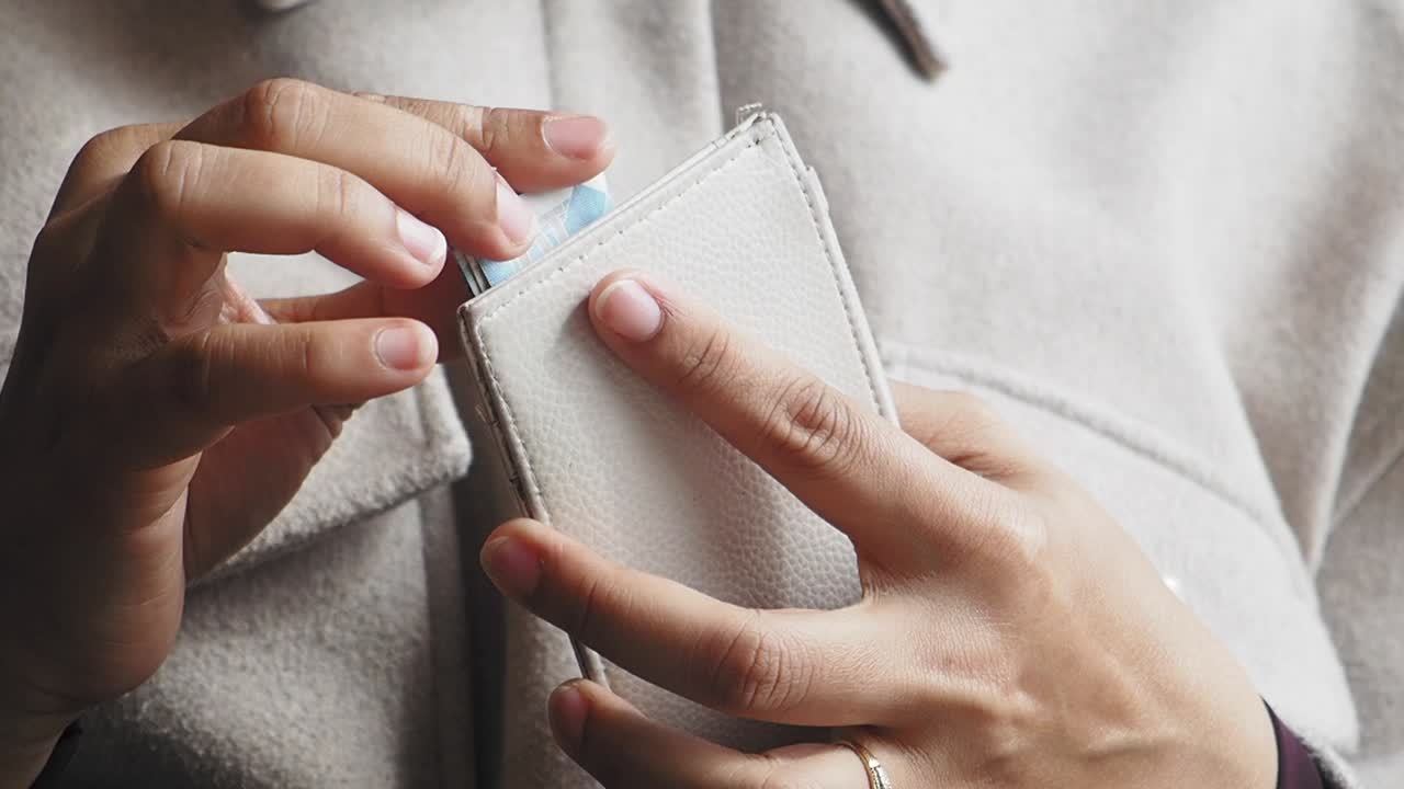 Close-up of hands handling a wallet and money or card