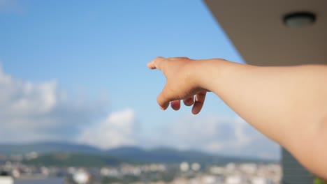 hand pointing up at the blue sky with clouds