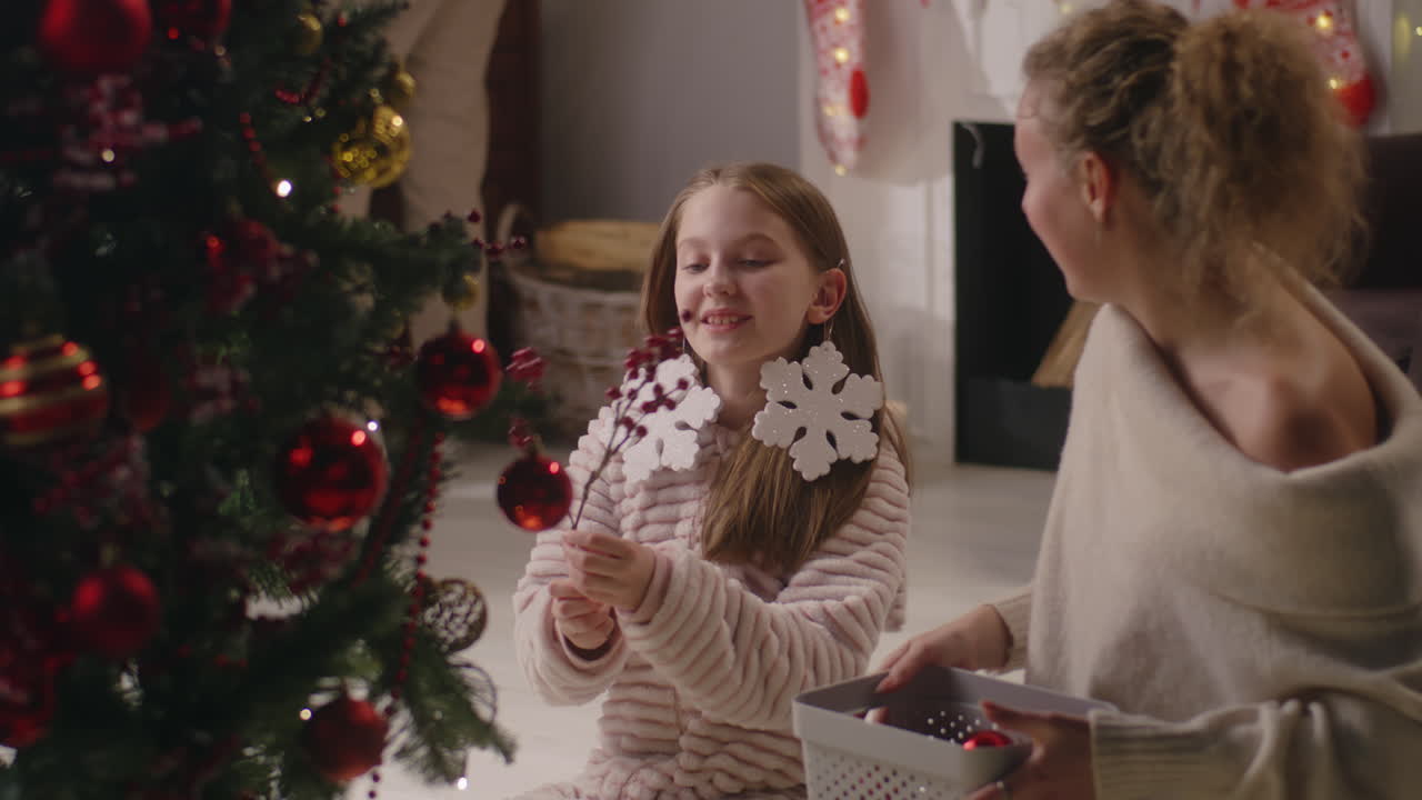 어머니 와 딸 이 크리스마스 트리 를 장식 하고 있다