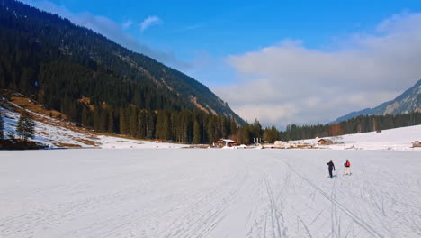 couple skiing at the foot of the mountain covered with pine-tree forest. skiing resort in the swiss alps. lichtenstein nature.