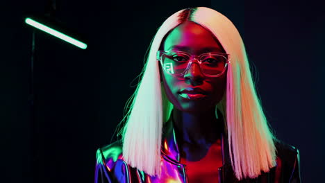 stylish woman with blonde hair and reflective sunglasses in neon lights