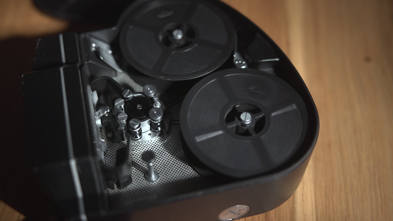 Vintage Film Projector Reels Spinning Under Warm Light, Textured Metal Spindles And Hubs, Rhythmic Rotation, . Media