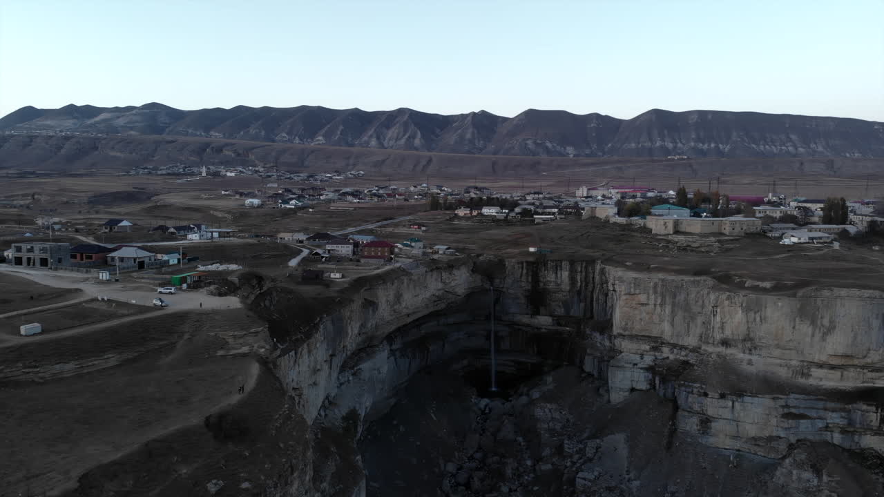 Waterfall in a Cliff Landscape with Mountains and Village