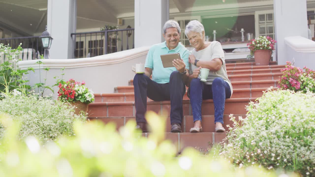 정원에서 태블릿을 사용하는 행복한 두 인종의 노인 부부의 비디오