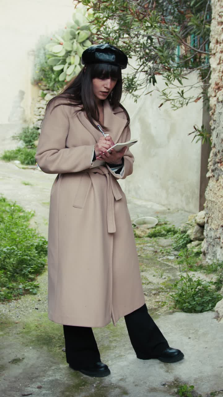 Donna sotto l'arco di un borgo medievale che prende appunti