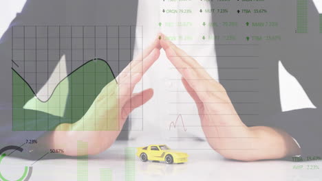 Animación-Del-Procesamiento-De-Datos-En-Gráficos-Sobre-Una-Mujer-Caucásica-Refugiando-Un-Auto-De-Juguete-Con-Las-Manos