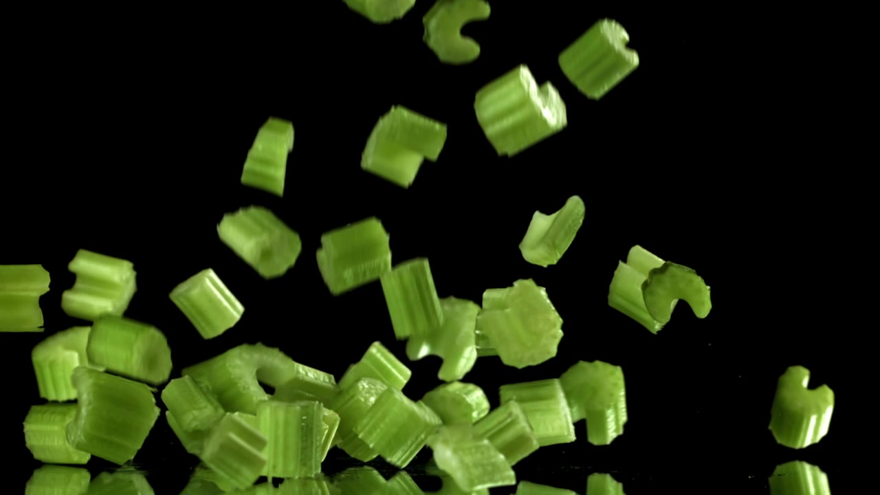 Fresh Chopped Celery Pieces Falling onto a Black Surface